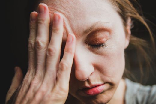 A woman is covering her face with her hand.