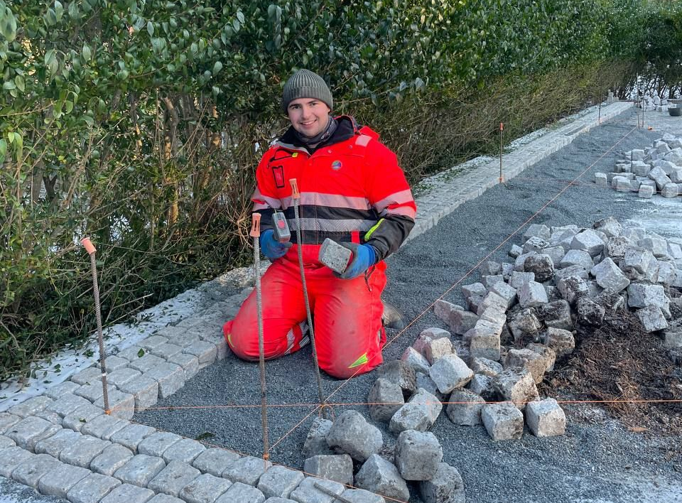 Mann som legger stein på gårdsplass