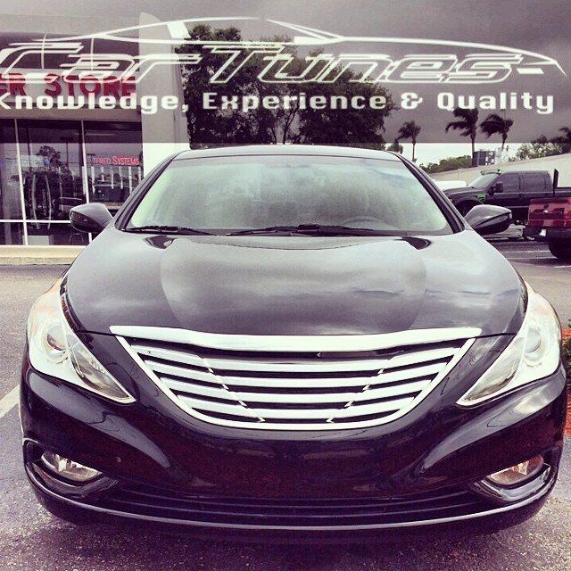 Black sedan with chrome grill parked in front of Car Tunes, with the words 