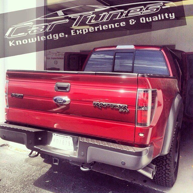 Red Ford Raptor truck backed up at a Car Tunes shop.
