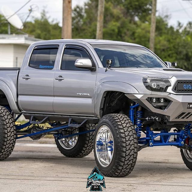 Silver lifted Toyota Tacoma truck with blue suspension.