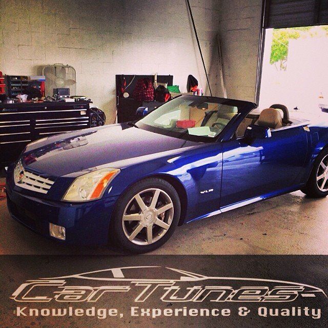 Blue Cadillac XLR convertible parked inside a garage with 