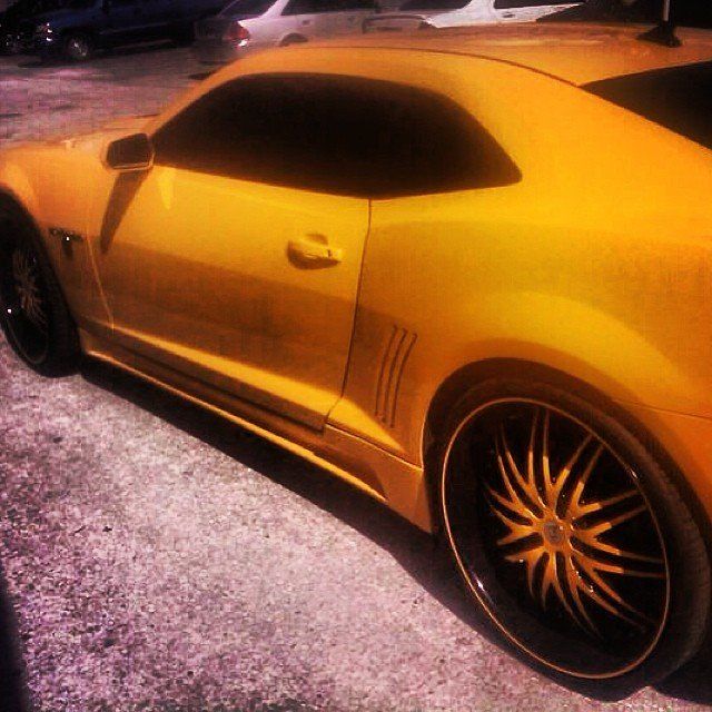Yellow Camaro sports car with black rims parked on concrete.