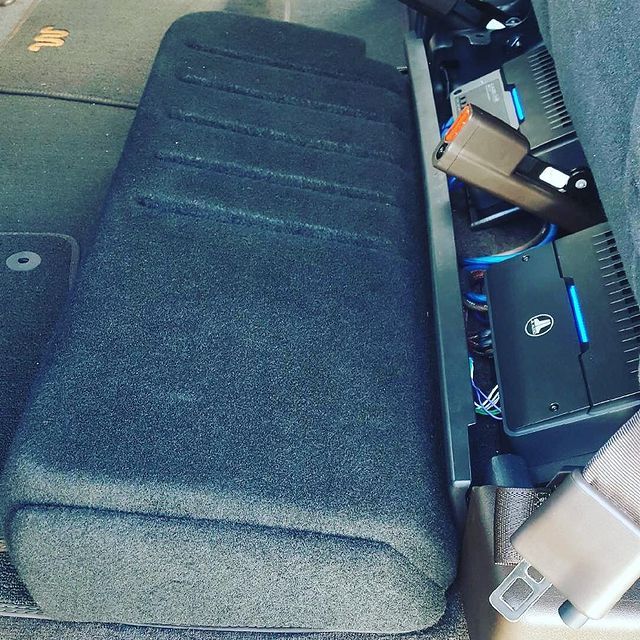 Car audio system: black subwoofer box and amplifiers installed under the rear seat.