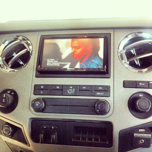 Dashboard with a car radio screen displaying a man's face, surrounded by vents and control buttons.