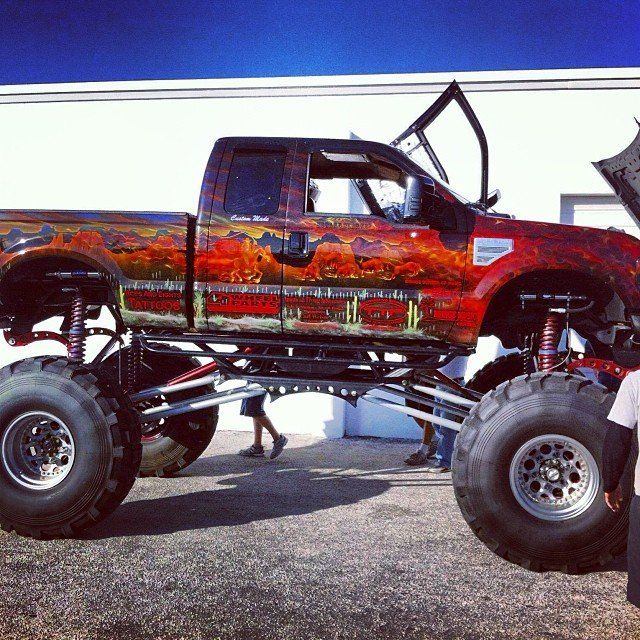 Monster truck with a custom paint job, raised suspension, and large tires.