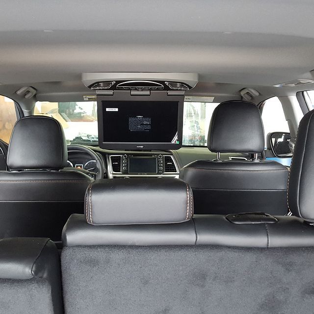 Interior of a vehicle with an overhead entertainment system and black leather seats.