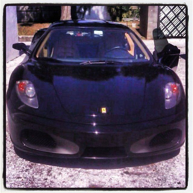Black Ferrari sports car parked on a stone surface.