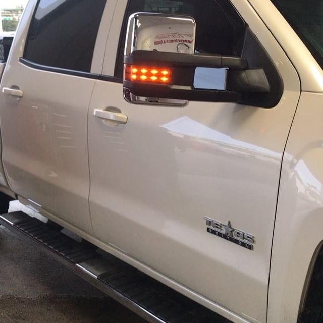 White truck side view mirror with orange LED lights.