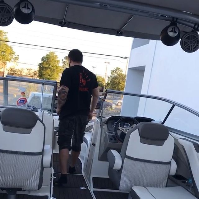 Man standing in boat, examining the cockpit with white and grey seats.