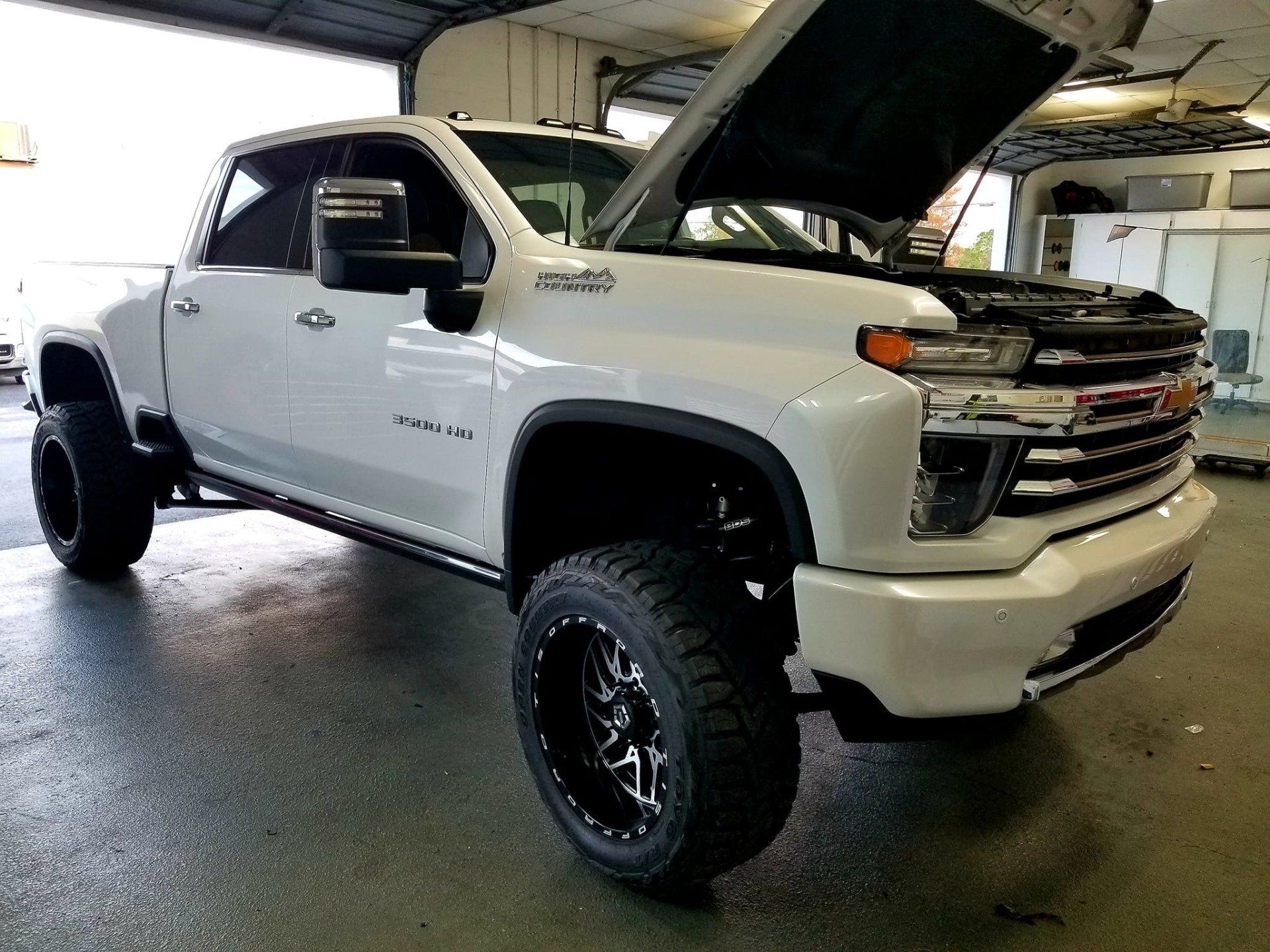 White Chevrolet truck with hood open in a garage.