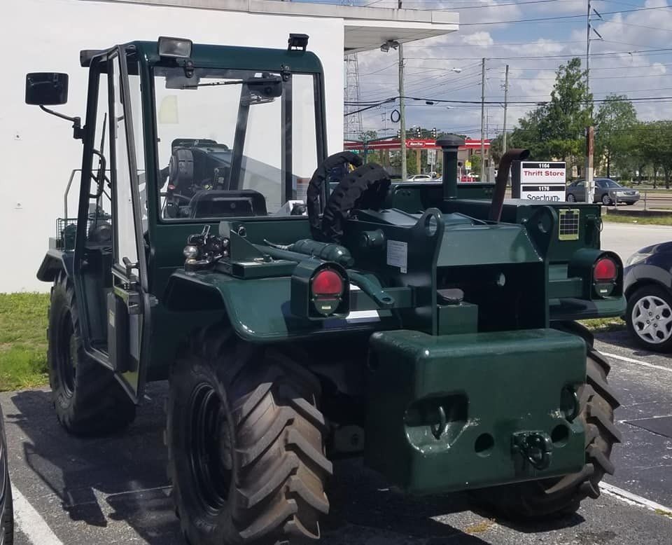 Dark green industrial tractor with a glass enclosed cab.