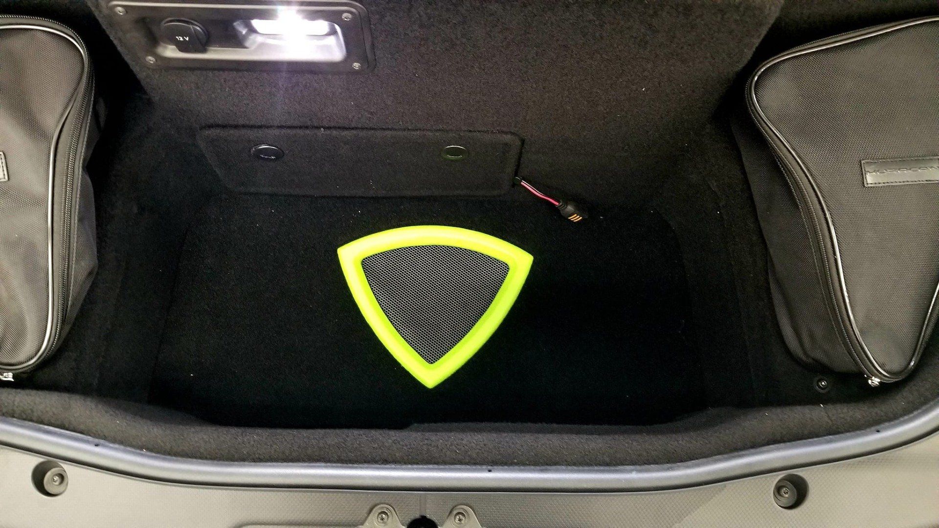 Black car trunk with a yellow triangle emblem and two storage bags.