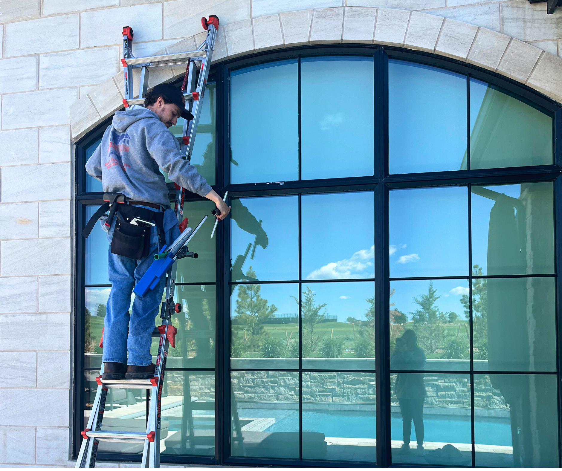 A man on a ladder is painting the side of a house.