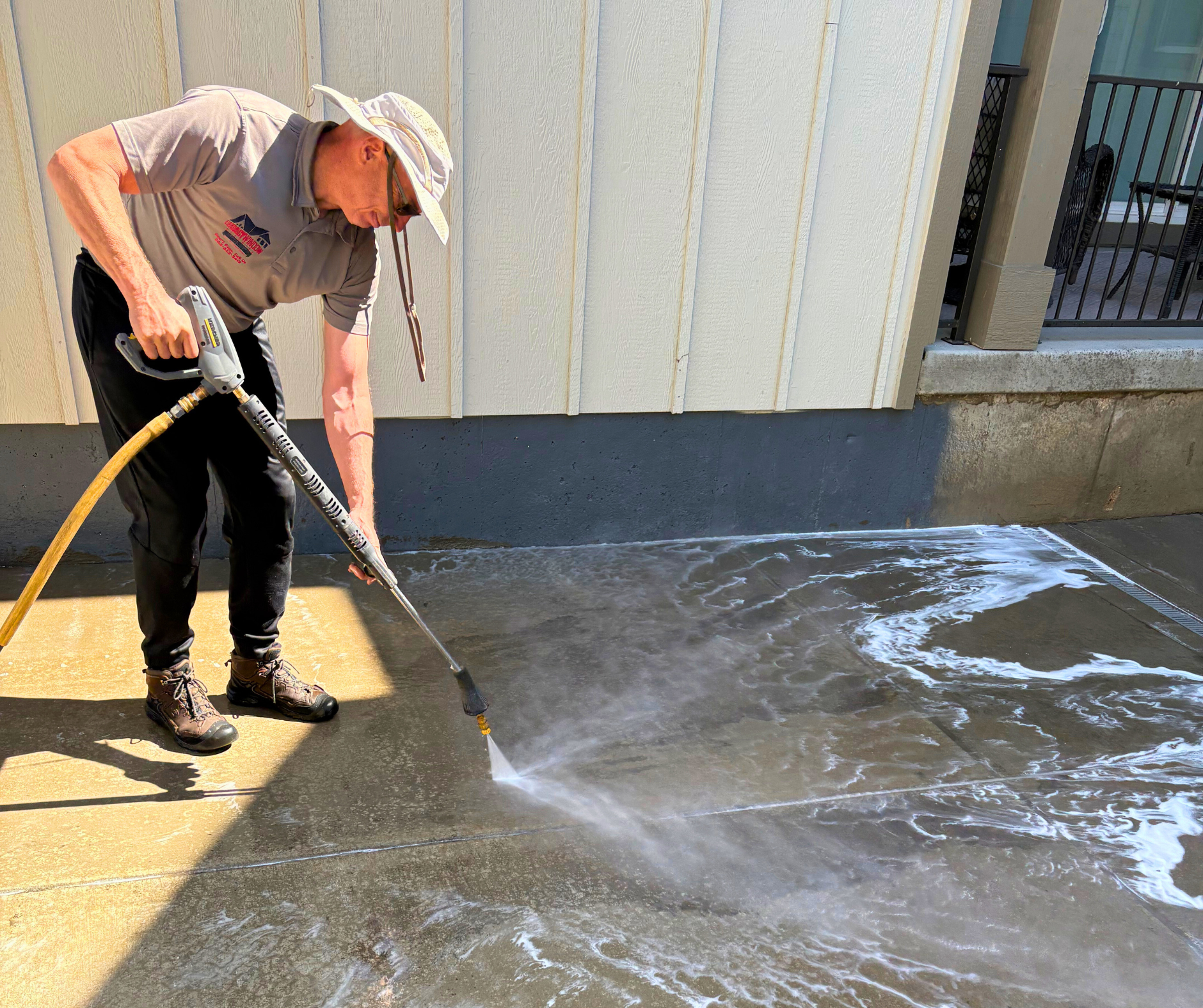 A man is using a pressure washer to clean a concrete surface.