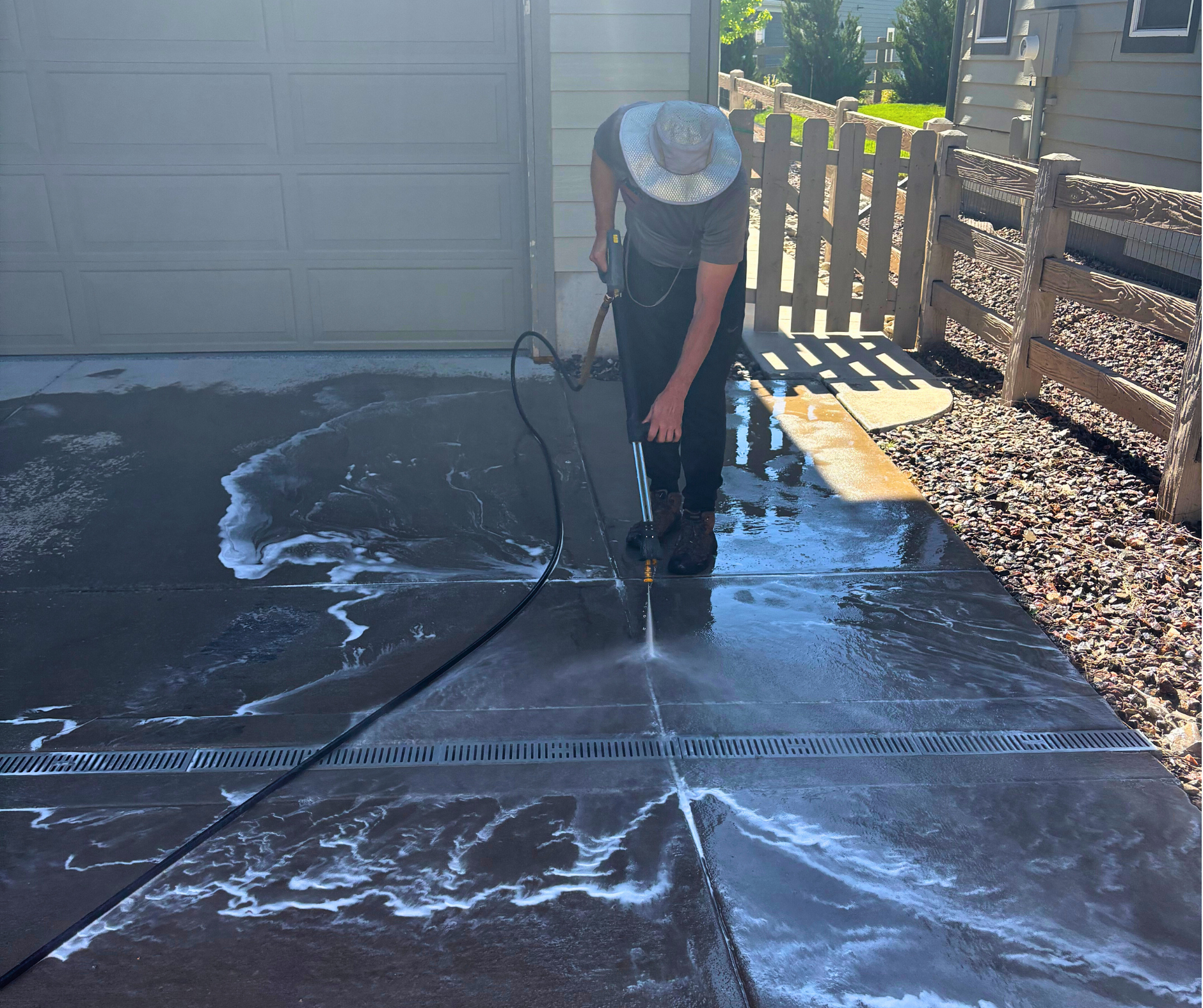 A man is using a pressure washer to clean a driveway