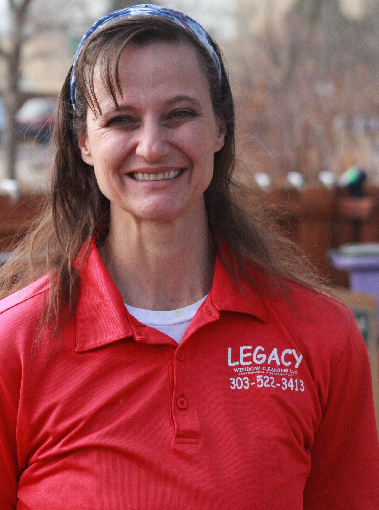 A woman is wearing a red polo shirt and smiling.