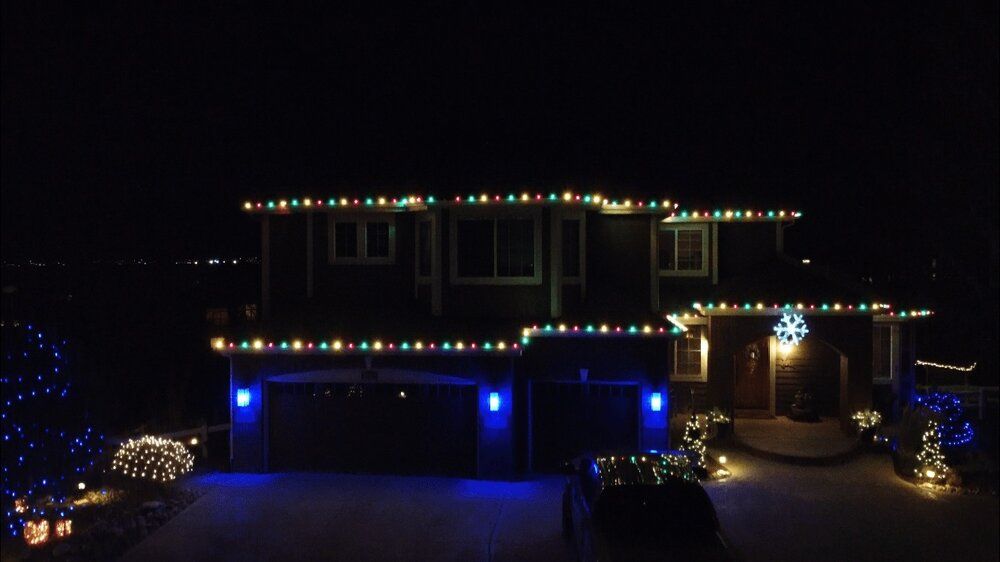 An aerial view of a house decorated with christmas lights at night