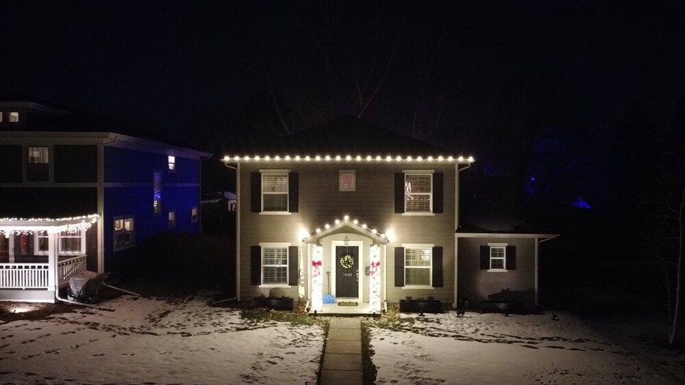An aerial view of a house decorated with christmas lights at night.