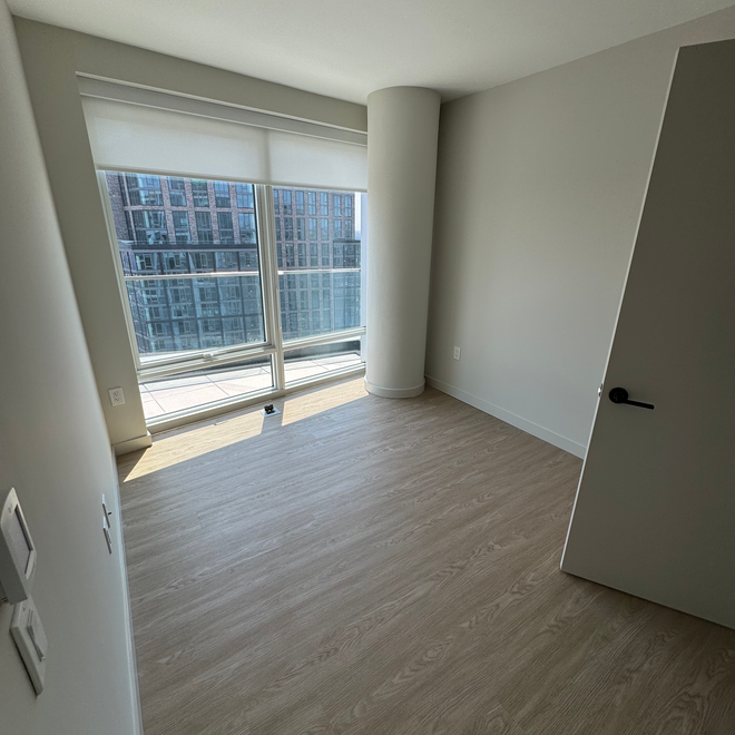 An empty room with a large window and a balcony.