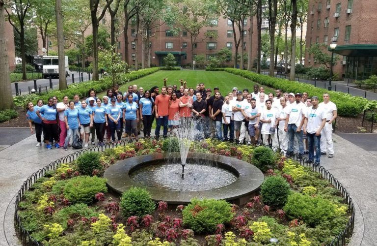 A group of people standing around a fountain in a park