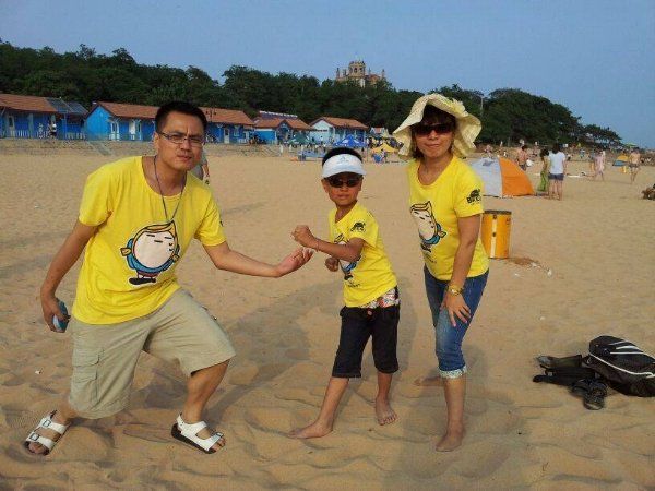 A family wearing yellow shirts standing on a sandy beach