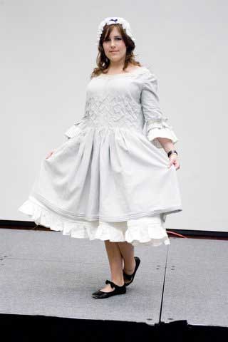 A woman is wearing a white dress and a white hat.