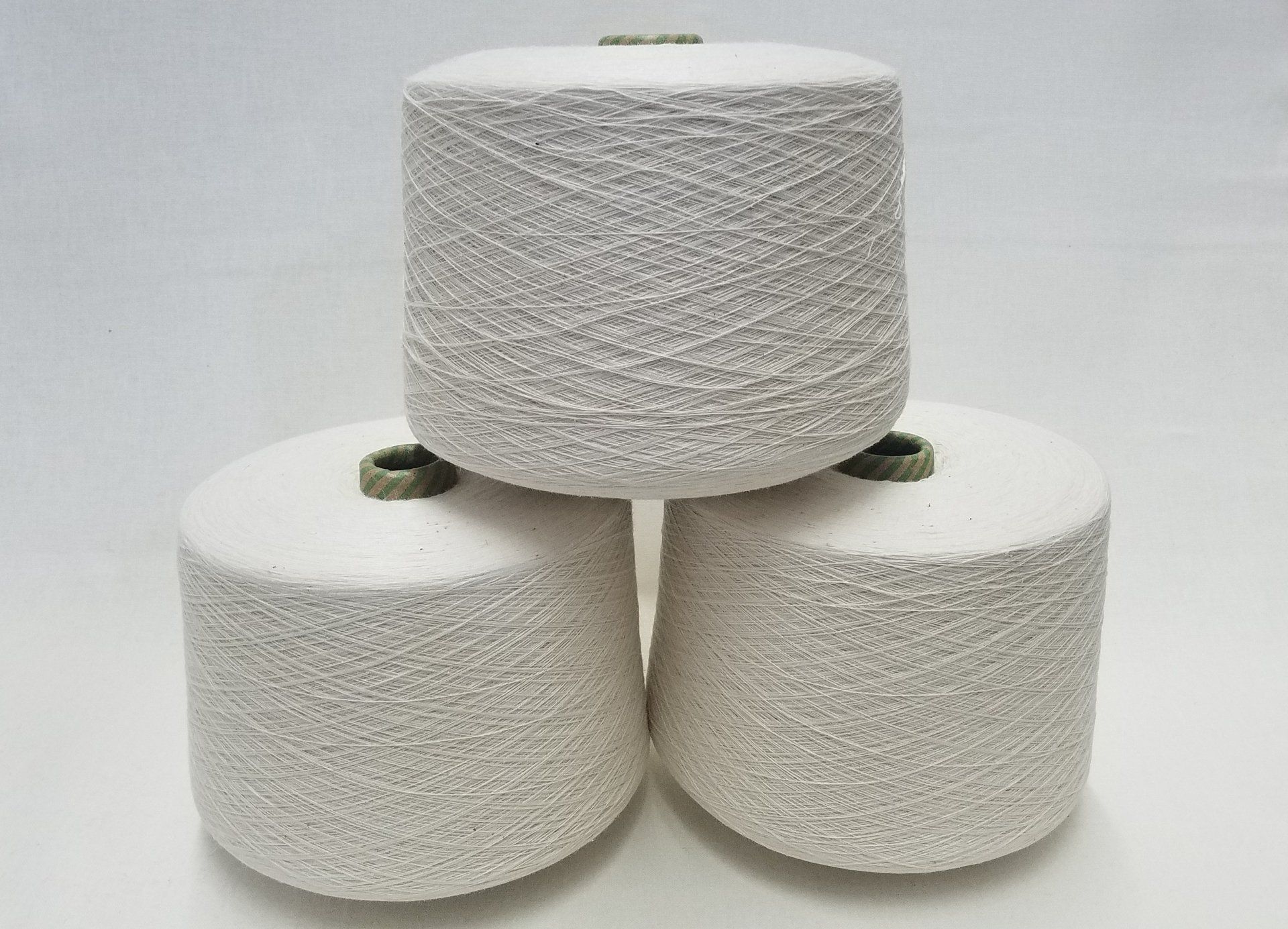 Three spools of white yarn are stacked on top of each other