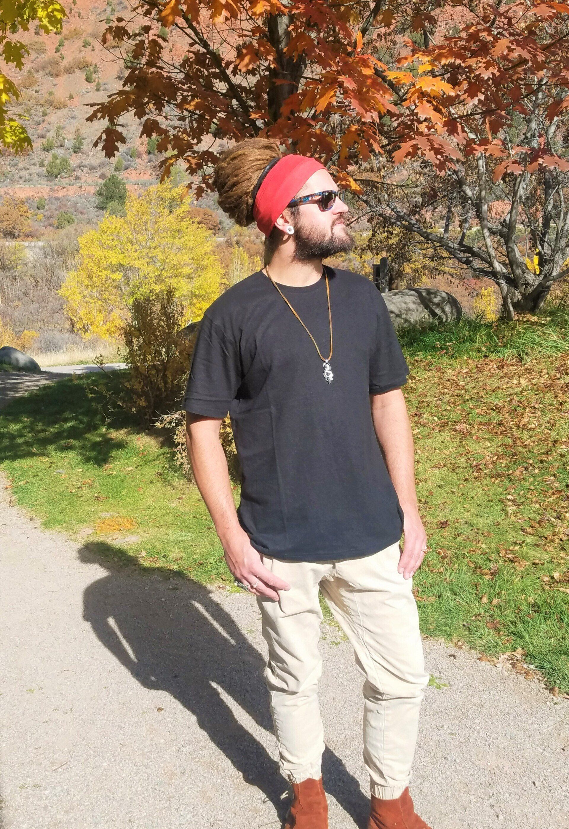 A man with dreadlocks and a red headband is standing on a path.