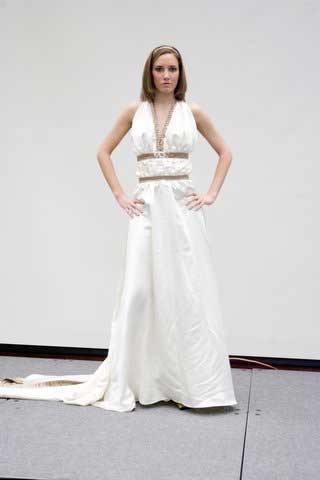 A woman in a white dress is standing on a stage with her hands on her hips.