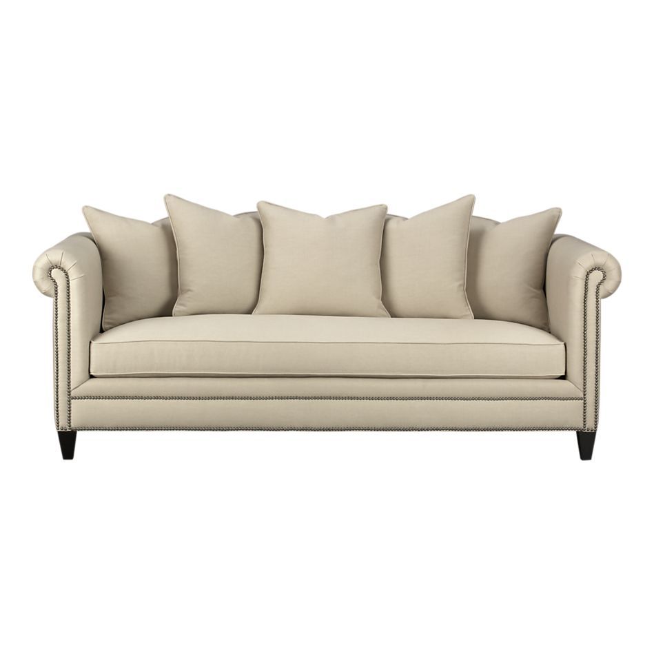 A beige couch with three pillows on a white background.