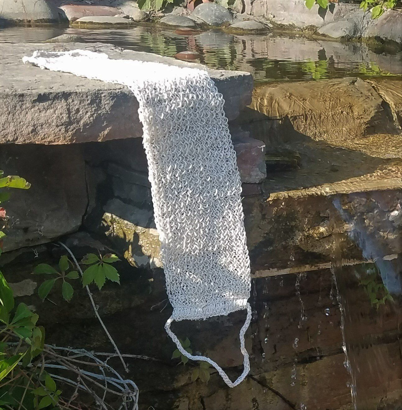 A white towel is hanging on a rock near a waterfall