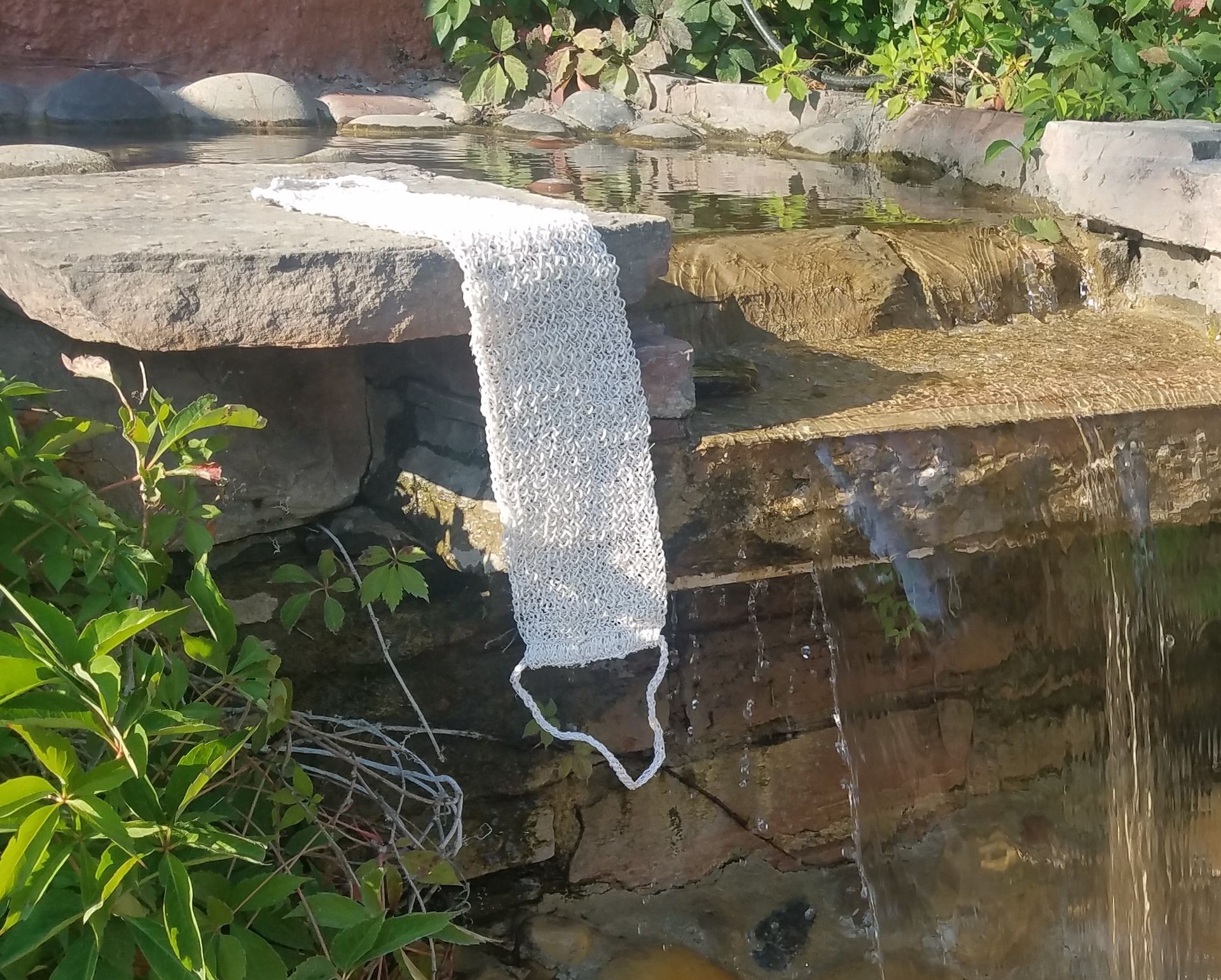 A white towel is hanging on a rock near a waterfall