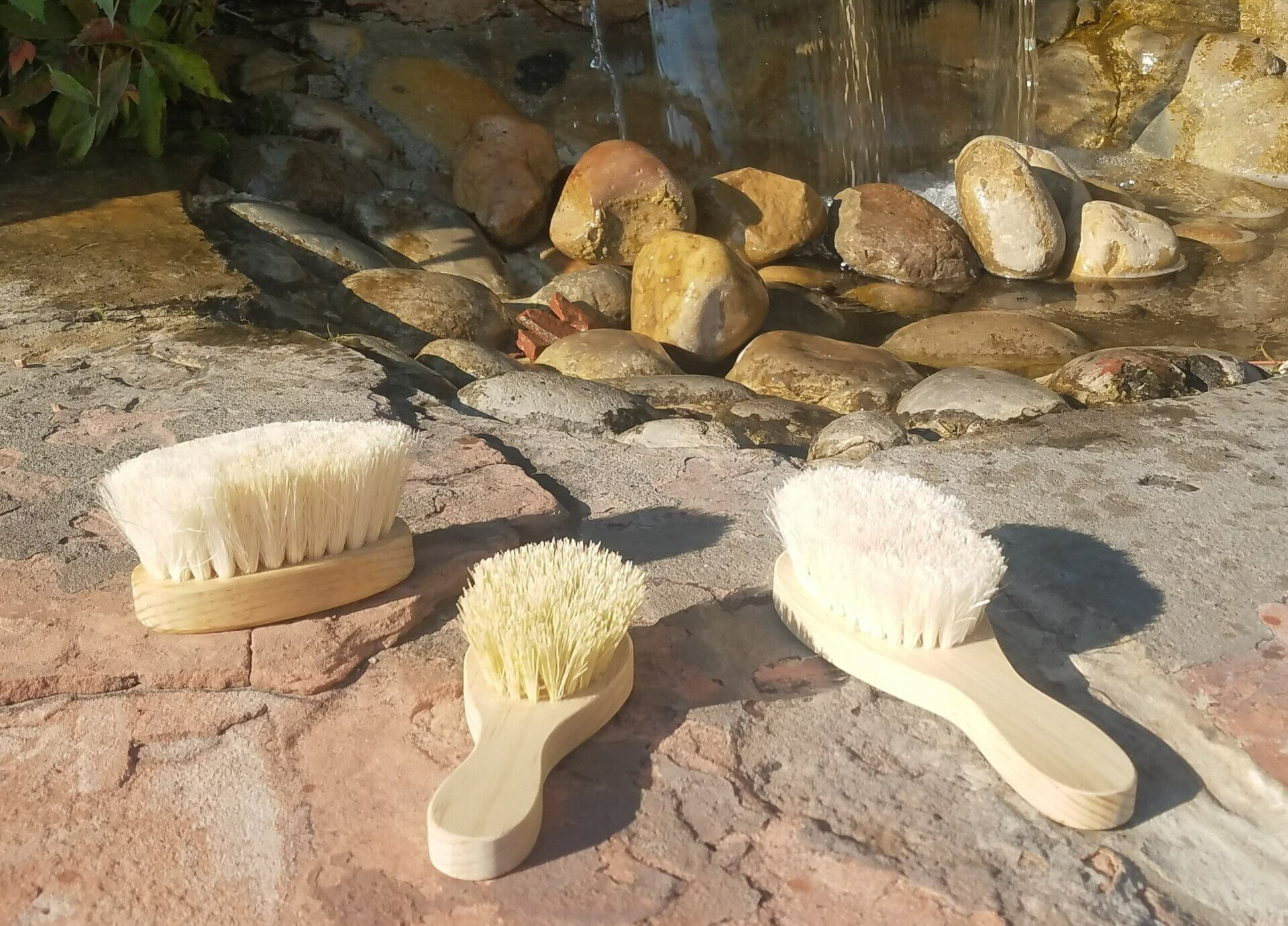 Three brushes are sitting on a rocky surface in front of a waterfall