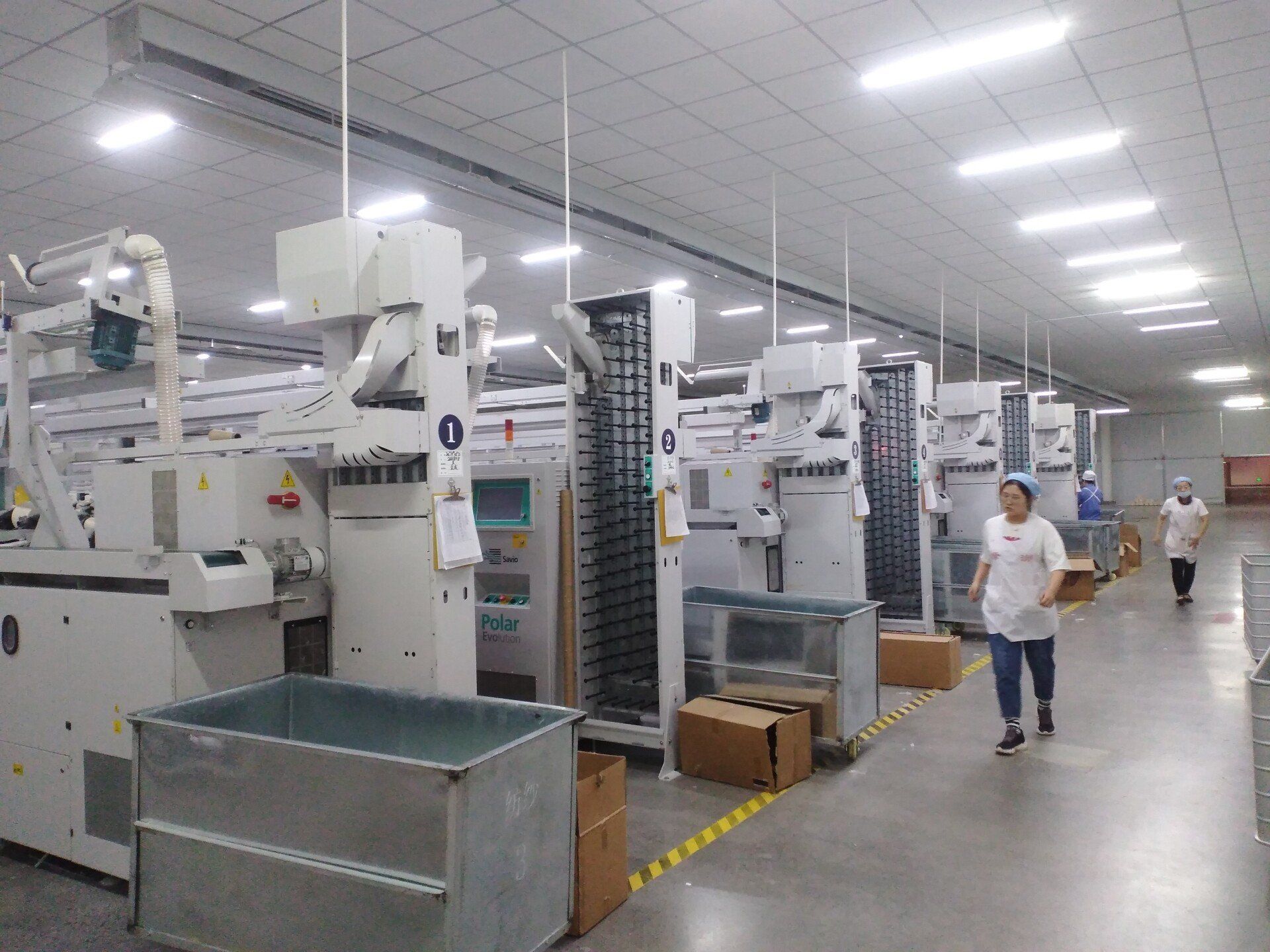 A woman is walking through a factory filled with lots of machinery.