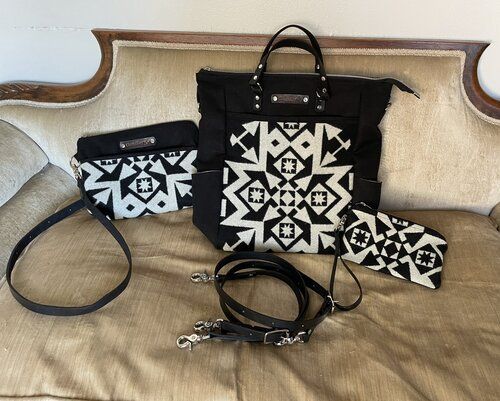 A black and white purse and wallet are sitting on a couch.