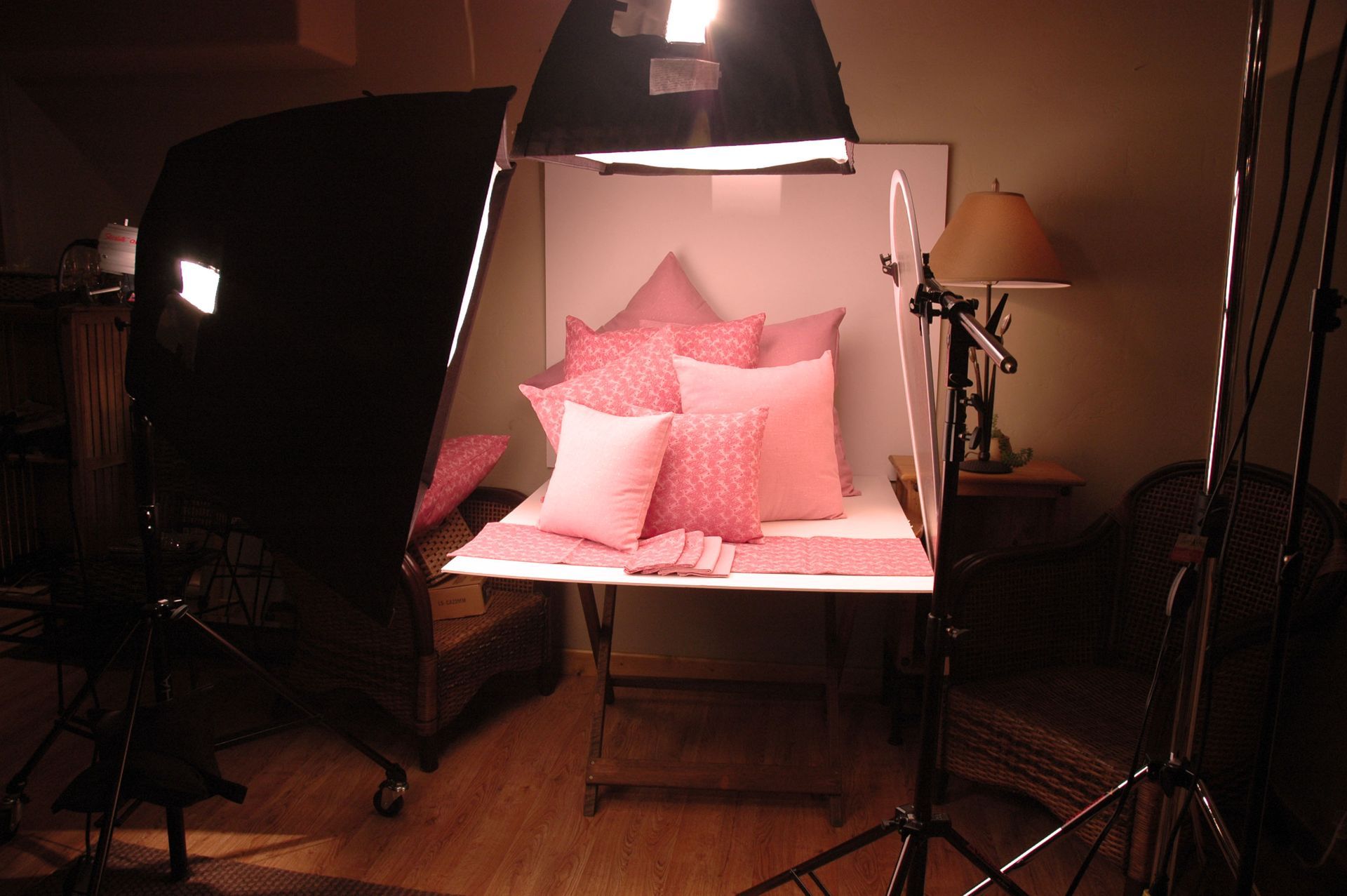 A bed with pink pillows and a lamp in a dark room