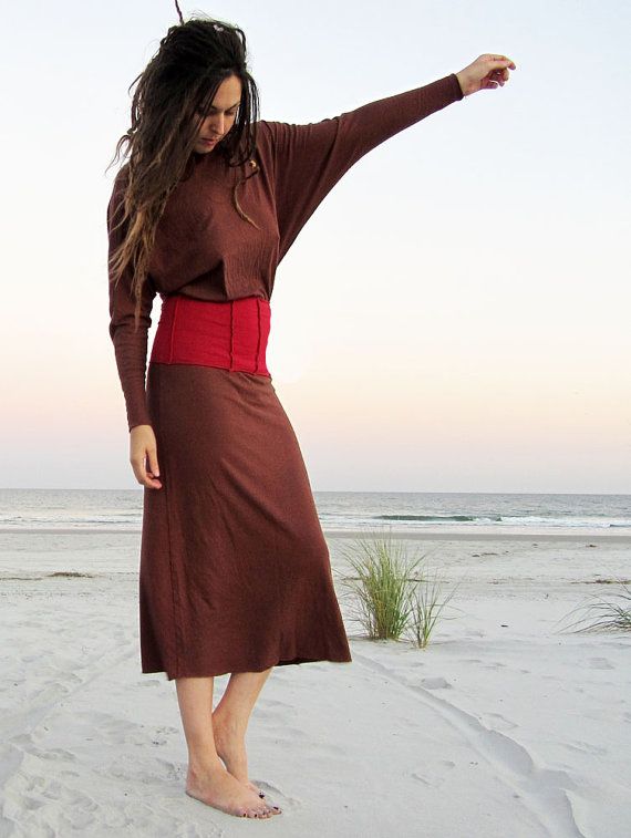 A woman in a brown dress is standing on a beach