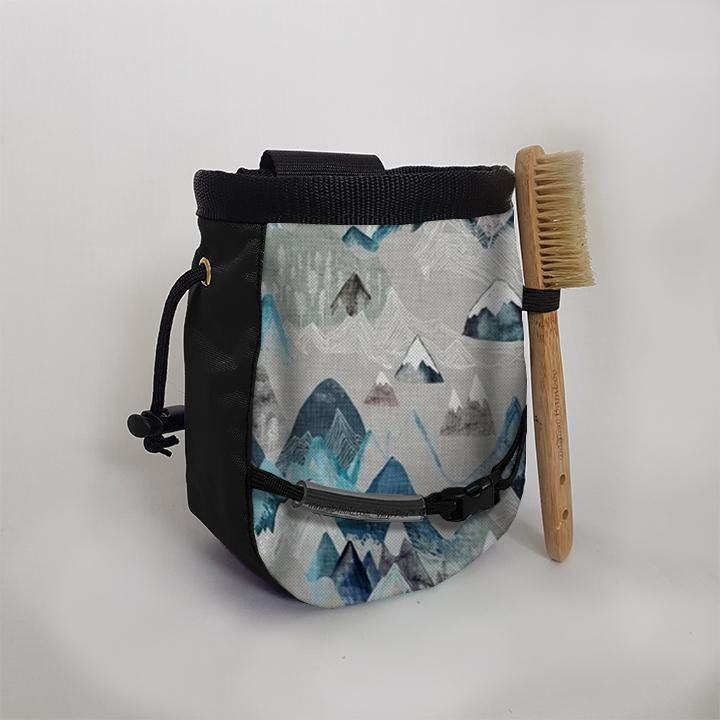 A chalk bag with mountains on it next to a toothbrush