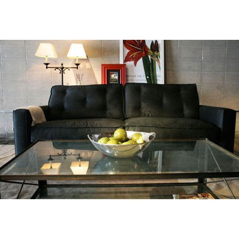 A living room with a black couch and a glass coffee table