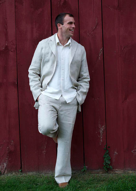 A man in a suit is leaning against a red wall.