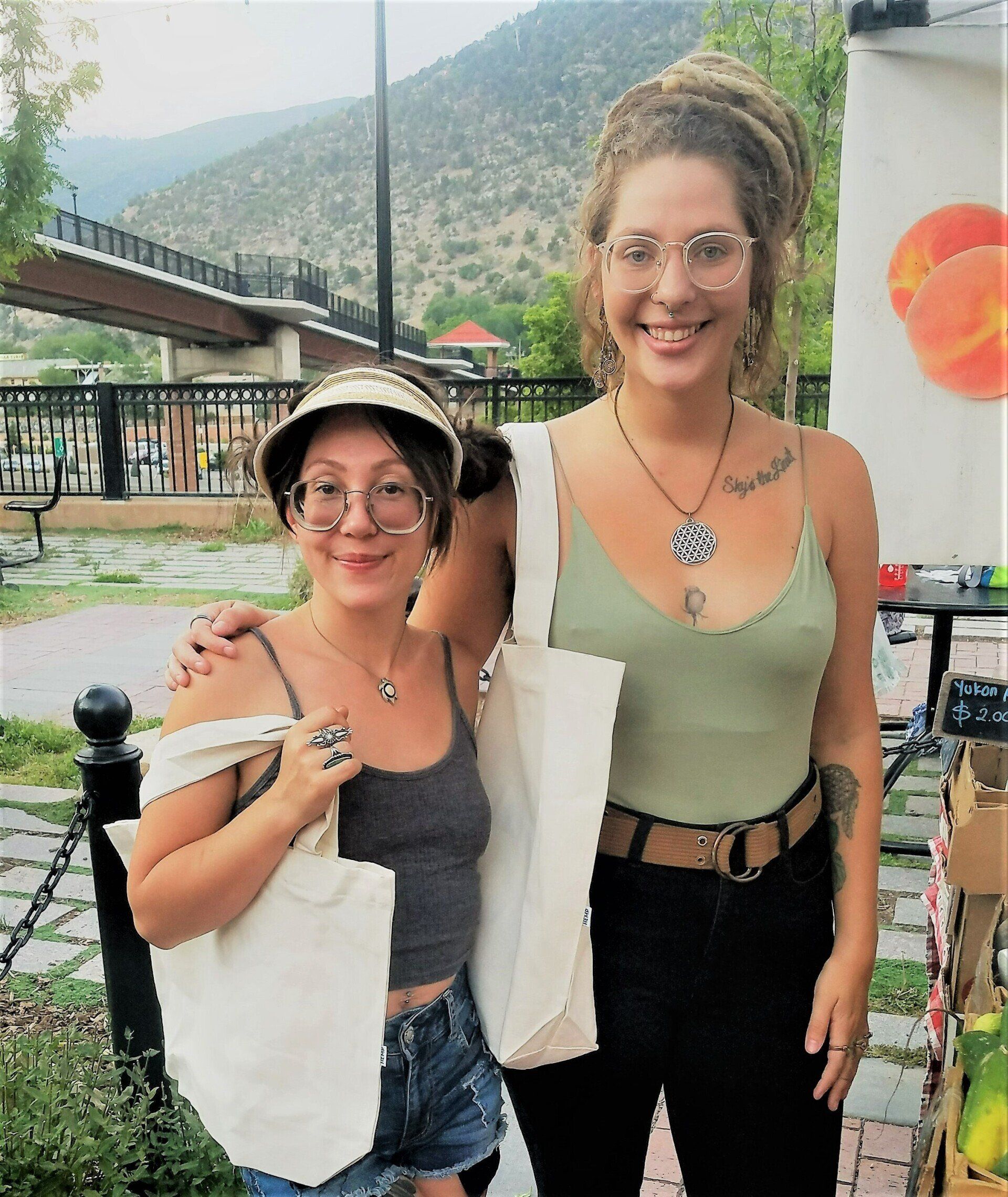 Two women are posing for a picture in front of a bridge