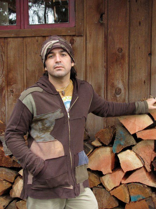 A man standing in front of a pile of logs