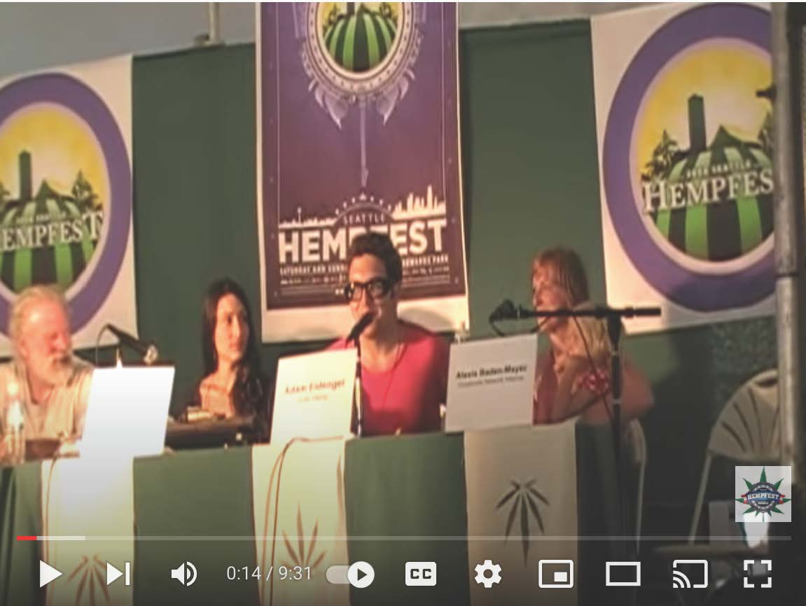 A group of people sitting at a table with a sign that says hempfest