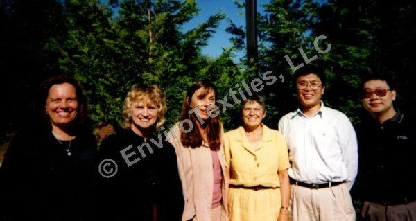 A group of people standing next to each other in front of trees.