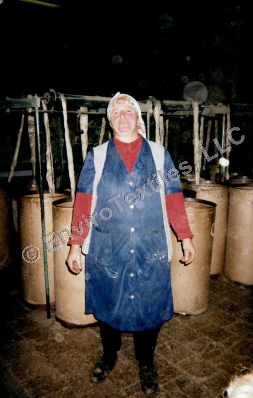 A woman in a blue coat is standing in front of a bunch of barrels