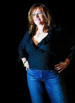 A woman in a black top and blue jeans stands with her hands on her hips