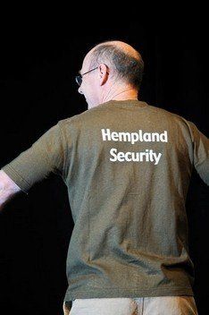 A man wearing a hempland security t-shirt with his arms outstretched.