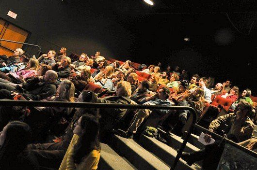 A large group of people are sitting in a theater watching a movie.