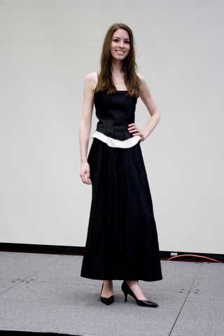 A woman in a black dress and heels is standing on a stage.